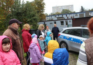 Przedszkolaki z wychowawcami przed radiowozem policyjnym